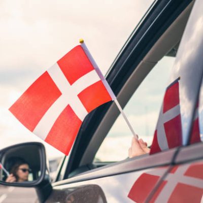 Woman or Girl Holding Danish Flag from the open car window. Denmark. Concept